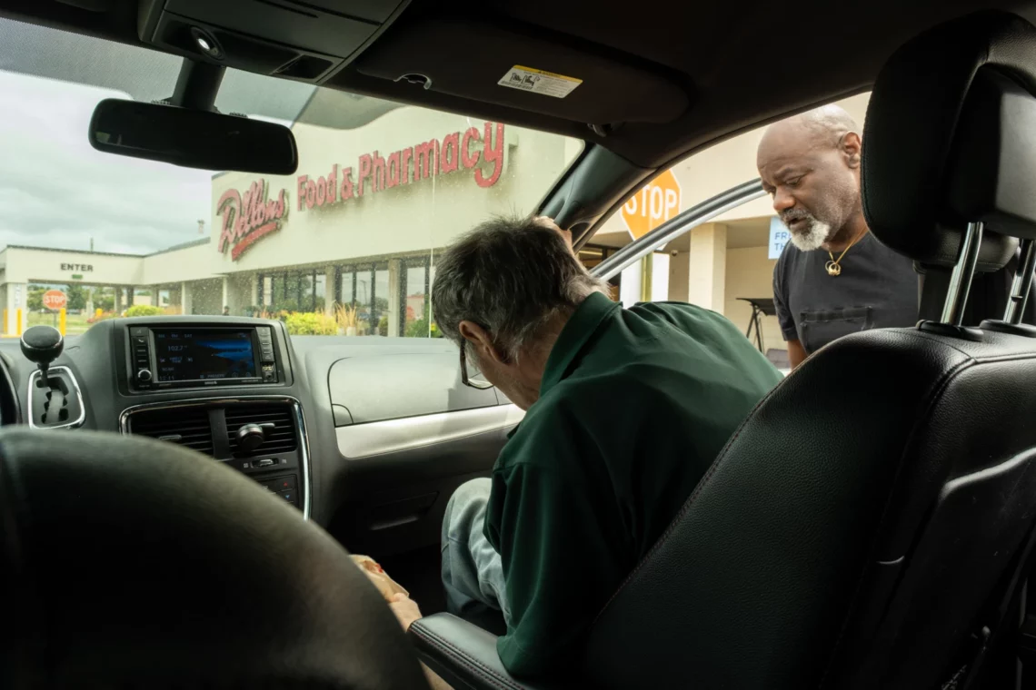 Photo from the backseat of a van of Floyd Coleman helping Mark Daldegan get into a minivan outside the Dillon