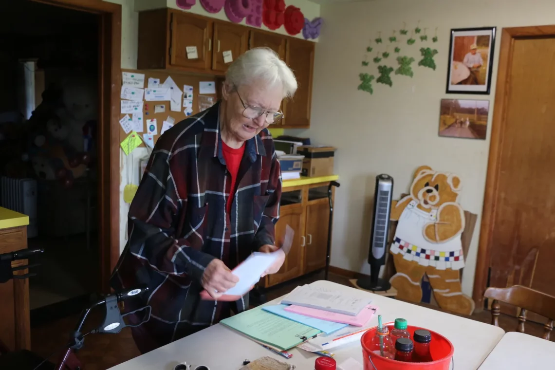 Mary Ellen McConnell, a white woman with white hair, is standing over her kitchen table. In front of her are documents related to fracking on her property.