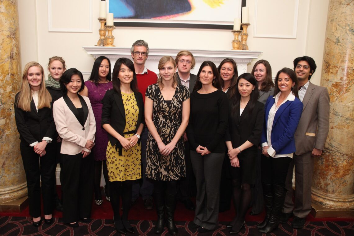 A group photo of the 2012 winners in front of a fireplace.