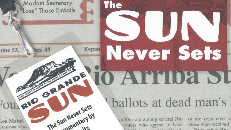 A close-up of a newspaper page shows a smart ID card badge labeled "RIO GRANDE SUN" atop the text. The phrase "The Sun Never Sets" stands out prominently in white and red in two different spots, while various headlines and text are visible in the background.