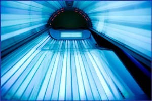 A glimpse from inside a tanning bed spotlighting the bright blue lights and the transparent acrylic surface where a person would lie down. The image captures both the tanning environment and the glow from the ultraviolet bulbs, reflecting an essential aspect of the tanning industry.