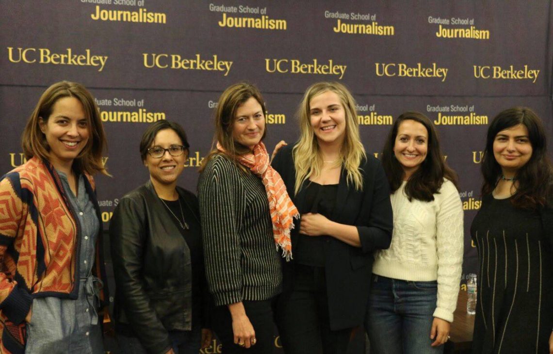 A group of six people stand together in front of a backdrop that reads 