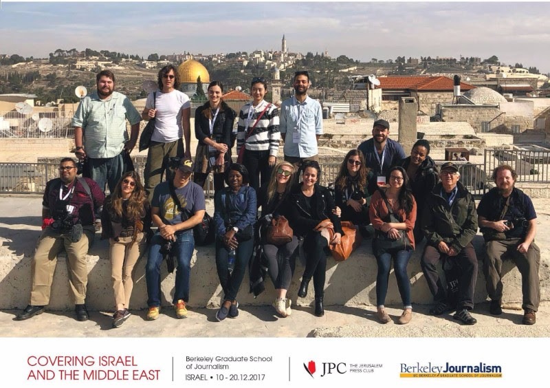 A diverse group of people poses for a photo in front of a historical backdrop featuring domed structures and ancient architecture. Text at the bottom reads 