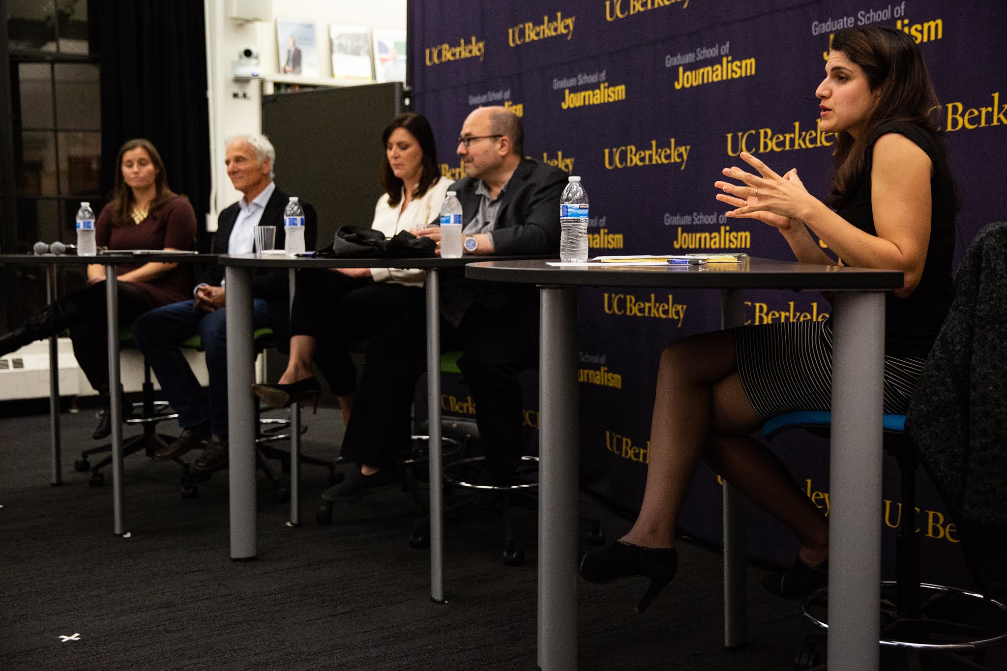 Photo of three women and two men seated at a long table on a panel.