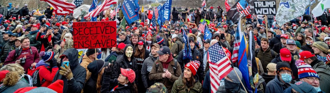A large crowd of people, many wearing red hats and holding American flags, gather for a protest. Signs include messages like "Liar of the Deceived, Home of the Enslaved" and "Trump Won." The atmosphere appears tense with a mix of expressions among the people, as Berkeley Journalism covers the scene.