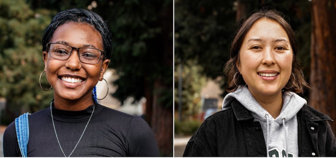 Two young women outdoors, each smiling at the camera. The woman on the left wears glasses, hoop earrings, and a black top with a blue backpack strap visible—a quintessential Berkeley Journalism student look. The woman on the right has short hair and wears a white hoodie and black jacket. Trees are blurred in the background.