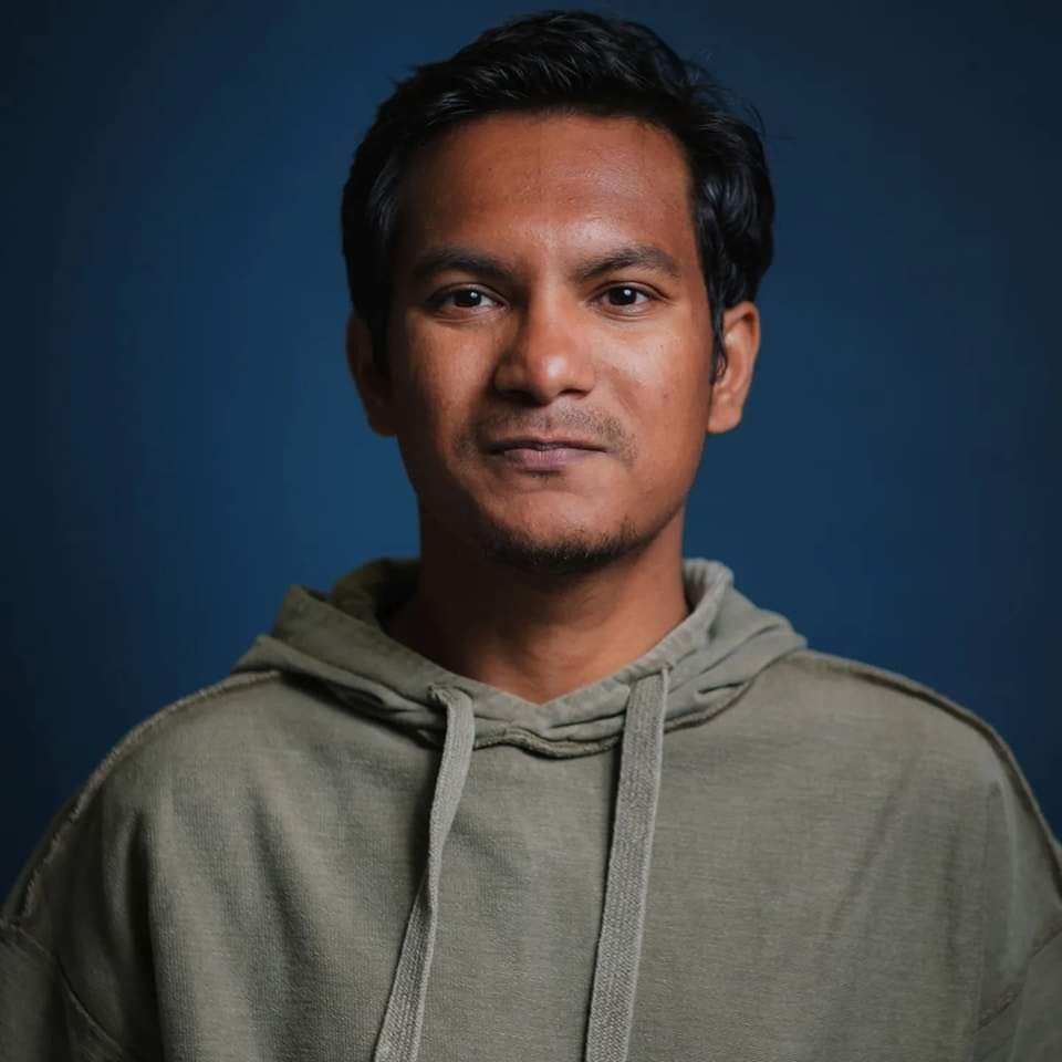 Photo of journalist Nazmul Ahasan wearing a green hoodie in front of a deep blue background.