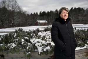 Jennifer Hubbard, a white woman wearing a black coat stands in front of Animal Sanctuary which is snowy behind her. 