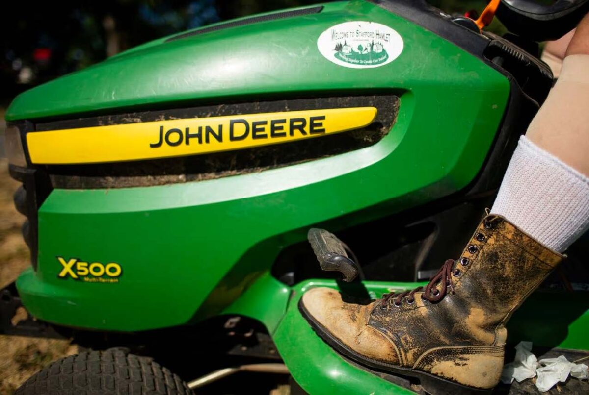 Photo of Rick Cook's boot on the pedal of his green John Deere tractor.