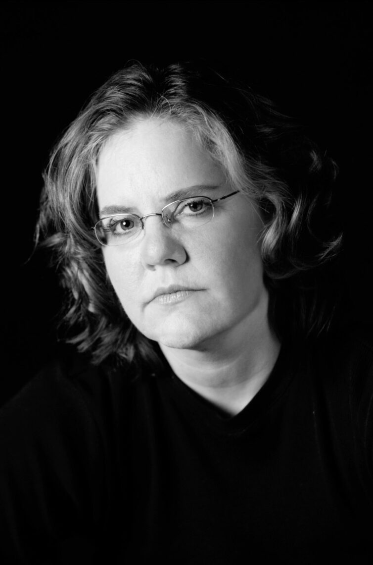 Black and white photo of journalist Jennifer LaFleur wearing glasses in front of a black background.