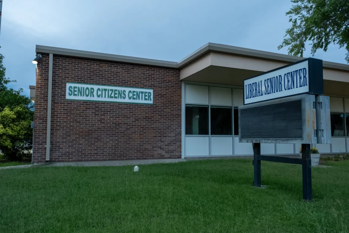 View of the front of the Liberal, Kansas Senior Center building. It is a brick building on a lawn with a sign reading "SENIOR CiTIZEN CENTER" in green capital letters.
