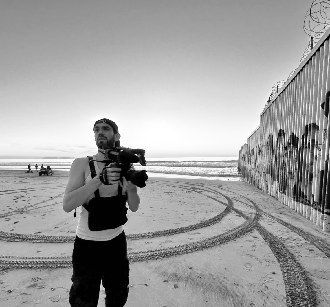 Black and white photo of Alfredo Torres on location in Mexico holding a camera.
