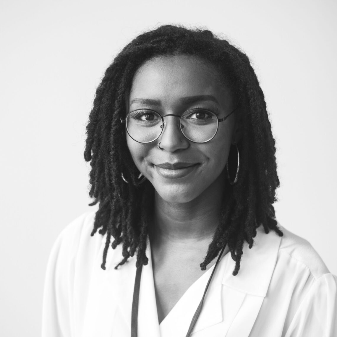 Black and white photo of producer Bria Suggs wearing glasses and a white jacket.