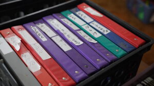 Photo of a drawer filled with binder folders of different colors. 