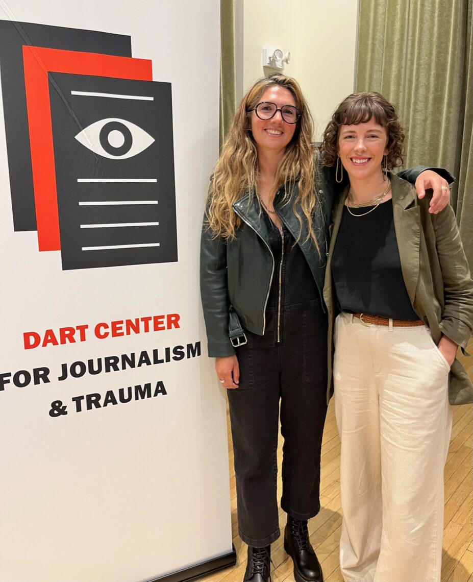 Meg Shutzer & Rachel Lauren Mueller standing in front of DART Center signage with their arms around each other smiling.