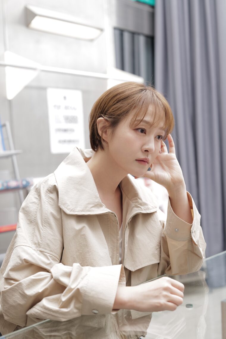 Photo of journalist In Jeong Kim wearing a light colored jacket with her hand near her face.