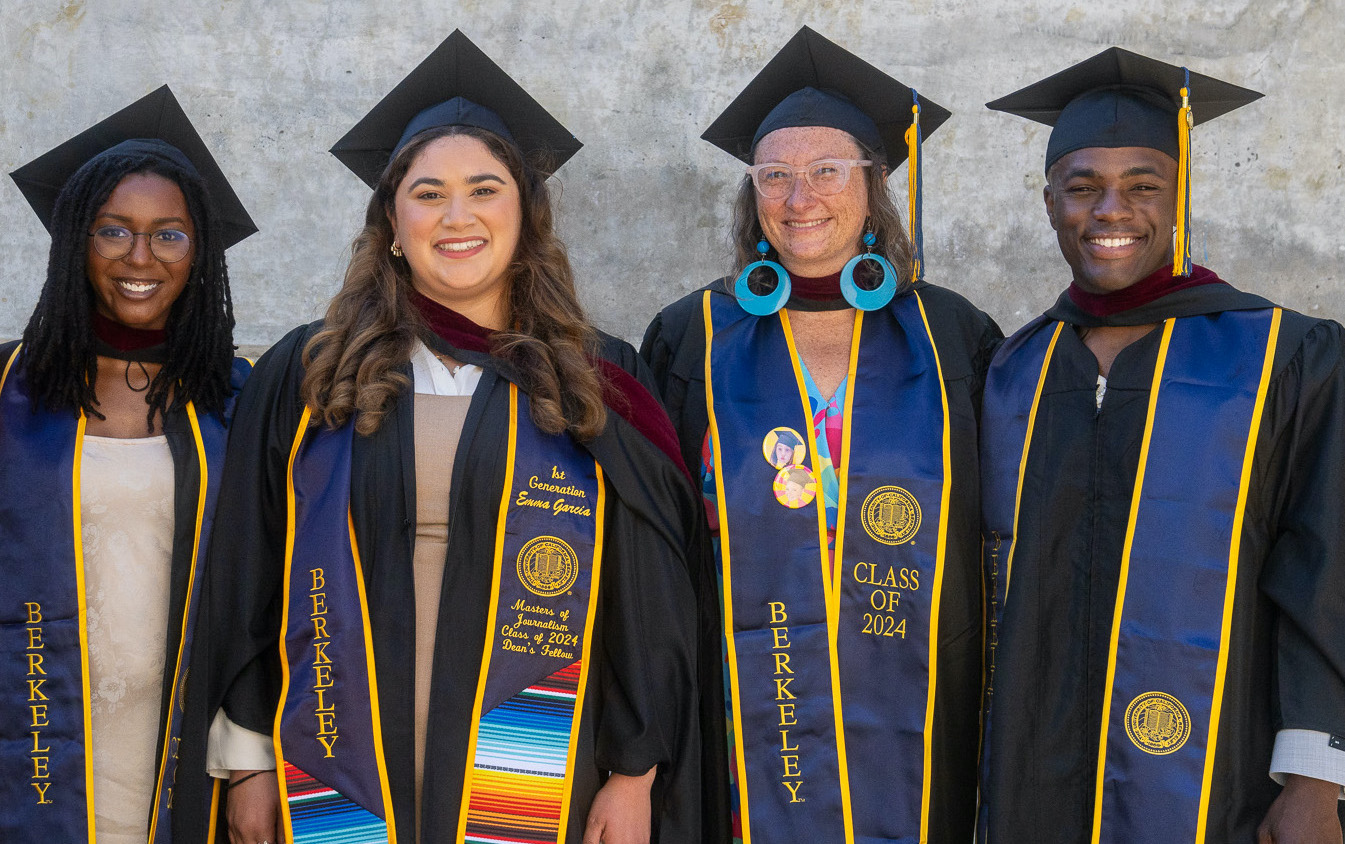 Four graduates wearing caps and gowns stand in a line, smiling. Three of the graduates don sashes emblazoned with "Berkeley," while the fourth proudly displays "CLASS OF 2024." They pose joyfully in front of a plain, light-colored wall, celebrating their university achievement.