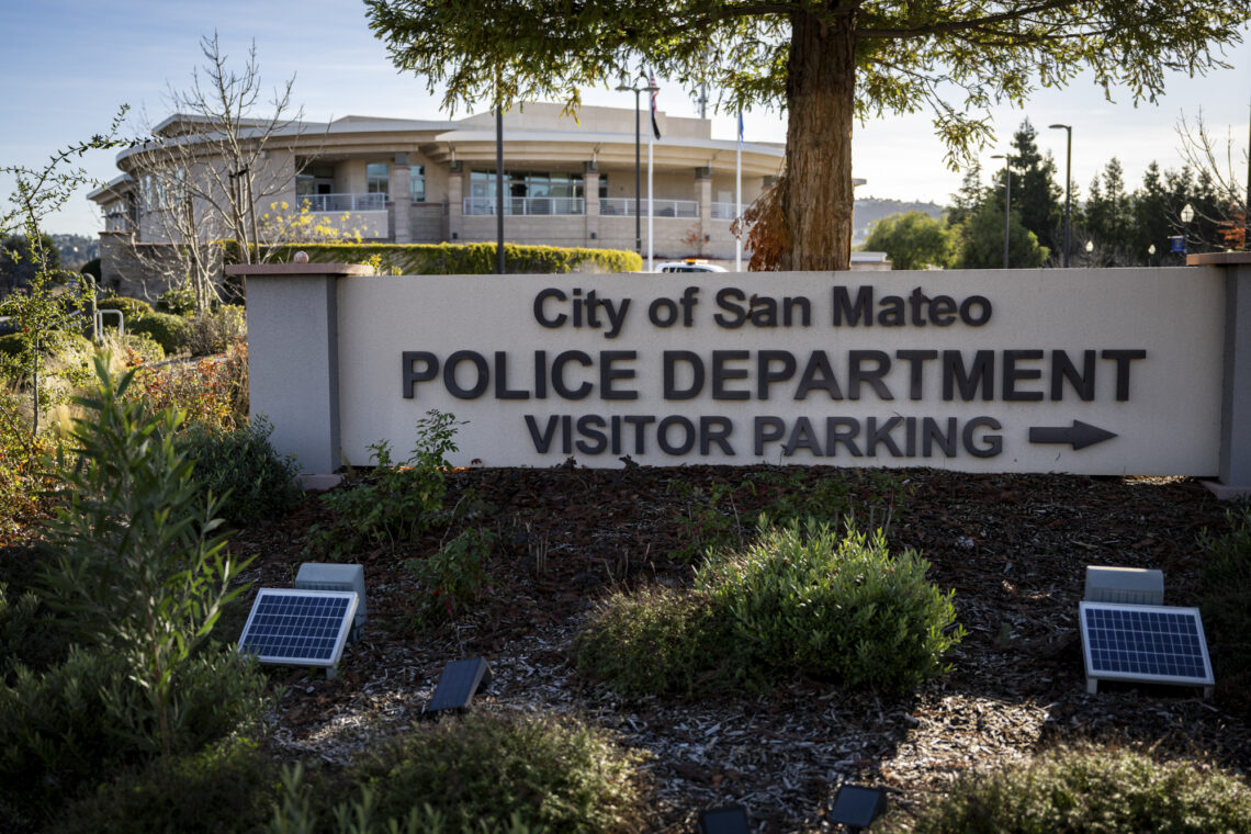 A photo of the sign outside San Mateo Police Headquarters that reads: City of San Mateo POLICE DEPARTMENT and below VISITOR PARKING and a right-facing arrow.