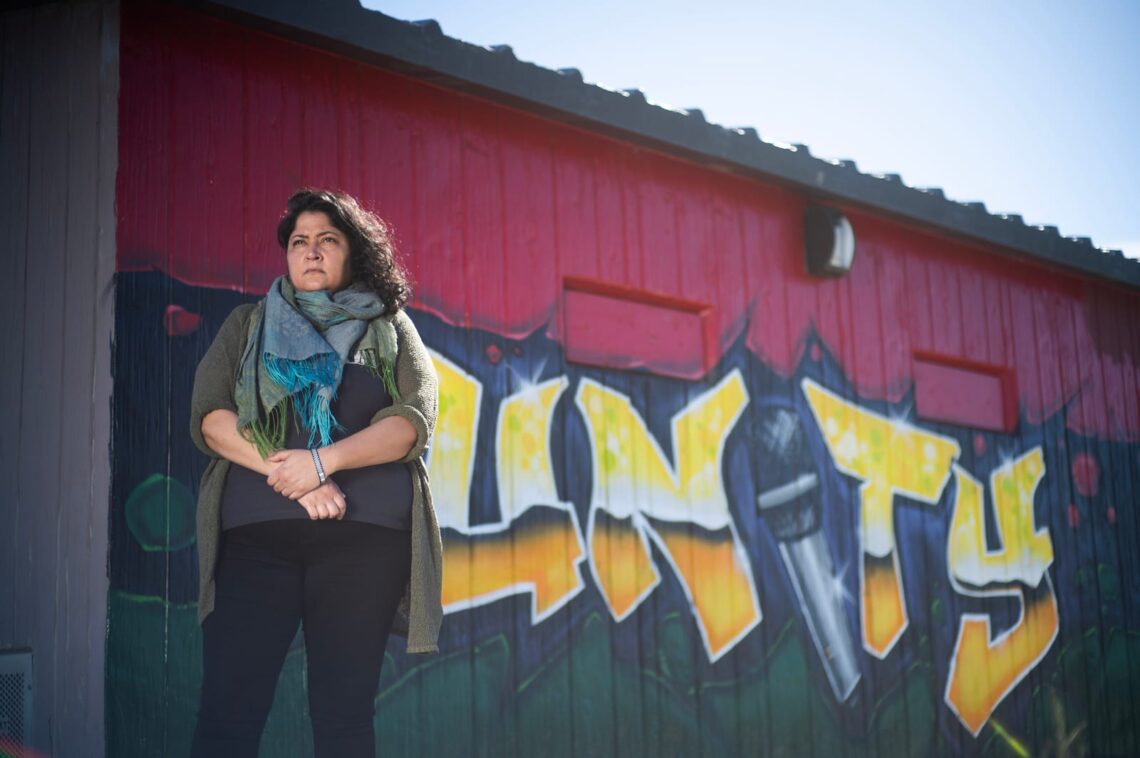 A person standing in front of a building with a mural that says "UNITY," captured by the city news site, highlighting stories that aren’t told.