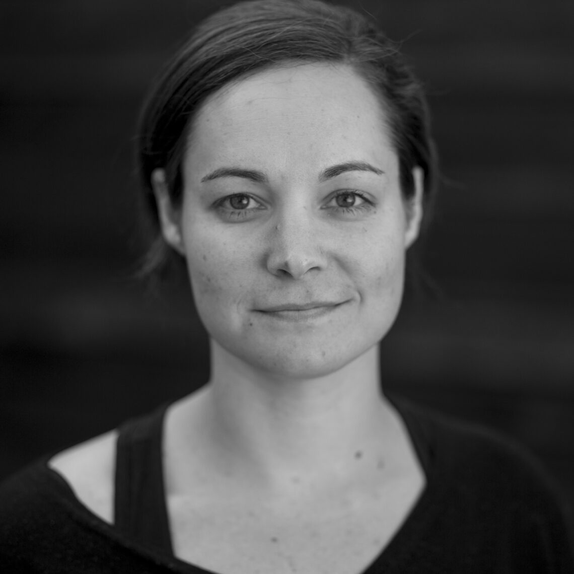 Black and white photo of a woman with short dark hair parted on the side looking directly at the camera smiling.