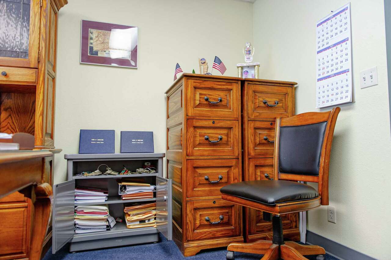 Photo of multiple cabinets, a large wooden cabinet and an smaller, open metal cabinet in Sheriff Mike Fisher's office.