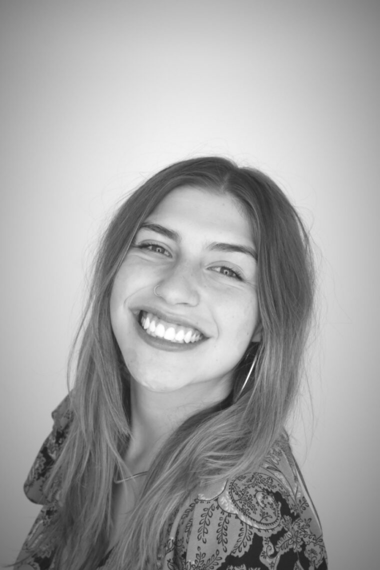 Black and white image of a young woman with shoulder length dark blonde hair with her head tilted back smiling.