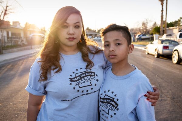 A young mother and son wear matching t-shirts on a street.