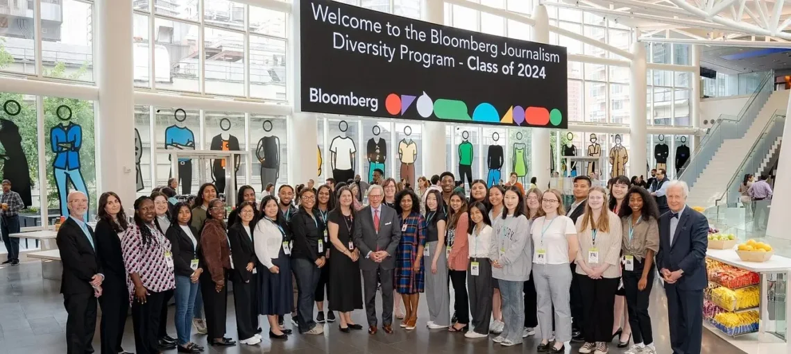 A large group of undergraduates stands together under a sign welcoming them to Bloomberg in 2024.