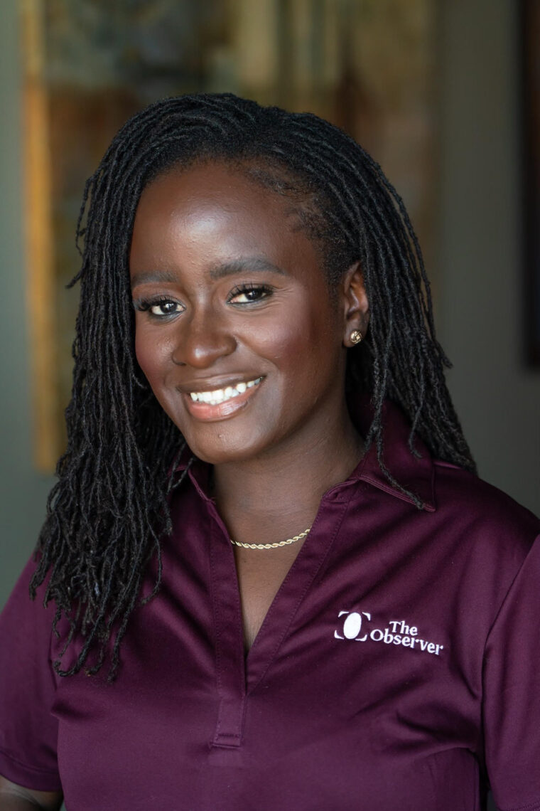 A beautiful African American woman with shoulder length hair wears a maroon polo shirt smiling.