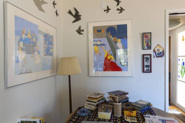 Inside of Ross Powers' home with art on the wall and books are piled on the table. 