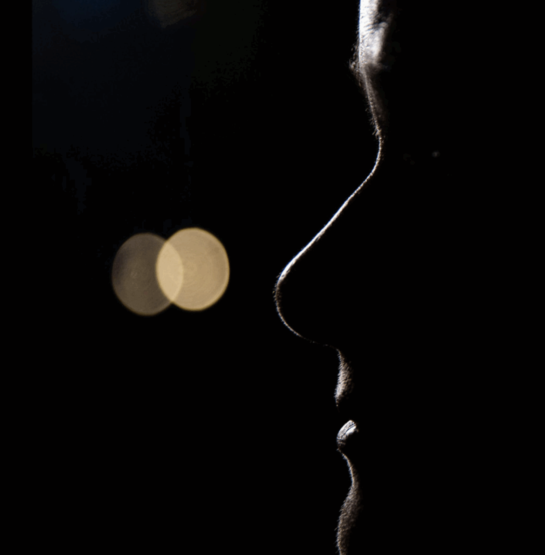 Dark photograph of a woman in profile with a neutral expression.