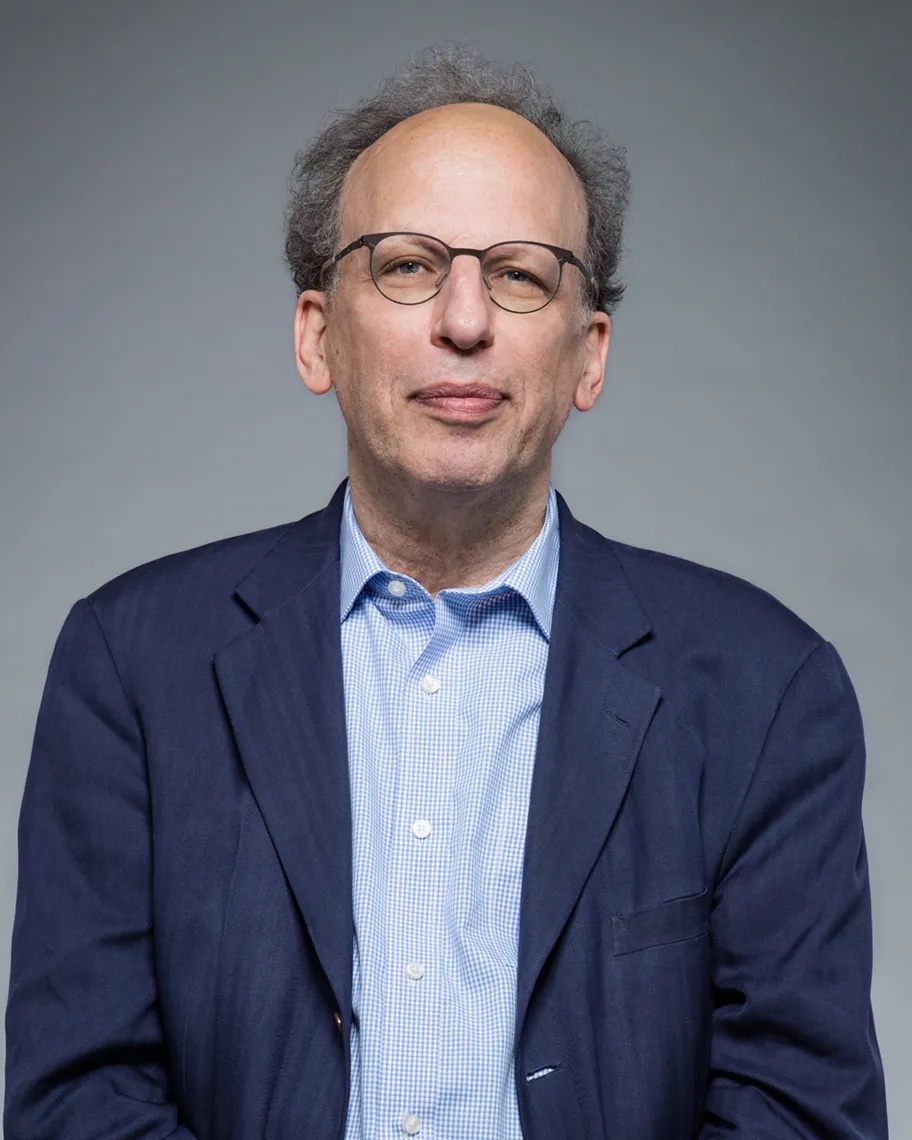Man wearing a blue suit jacket over a light blue shirt and wearing glasses.