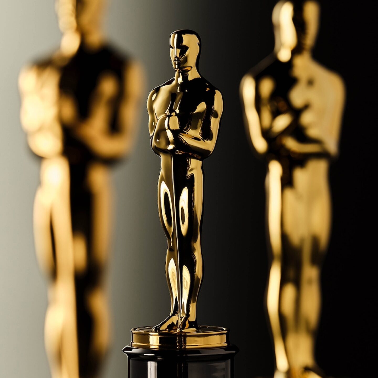 3 gold Oscar statues in front of a black background.